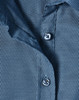 A close-up of a blue pin dot stretch 3/4 sleeve shirt featuring buttons and a fabric texture.