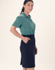 A woman is wearing a green polo shirt and a navy utility cargo skirt with pockets. The skirt has a fitted style.