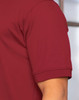 A maroon polo shirt with a short sleeve and a logo on the chest. The fabric appears smooth and lightweight.