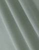 A close-up of light green cotton fabric with a smooth texture, showcasing fine weaves and folds.