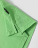 A green polo shirt featuring a logo and a textured fabric. Close-up of the collar and sleeve hem.