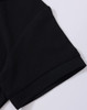 A close-up of a black polo shirt sleeve featuring a folded cuff and a subtle branding logo.