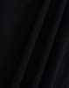 A close-up of a black fabric with a textured surface, featuring folds and draping. The image showcases the material's quality.