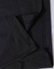 A close-up of black fabric showing the folded edge and stitching detail of a polo shirt. The fabric has a textured finish.