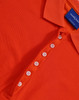 An orange polo shirt with a collar and a button placket. It features a branding label on the inside.