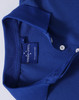 A close-up of a blue polo shirt, featuring a classic collar and buttons, with a label and a logo on the inside.