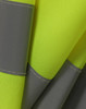 A close-up of a bright yellow safety vest featuring grey shoulder reflective tapes and textured fabric.