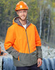 A Hi-Vis quilted two-tone safety jacket in orange and grey, worn by a man in a hard hat and safety glasses, outdoors.