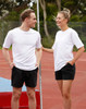 A white unisex short sleeve tee is displayed on a male and female model, set against an outdoor sports background.