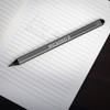 A grey stylus pen resting on an open notebook with a lined page. The pen features a logo and product name.