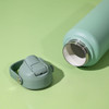 A drink bottle in a pastel green colour with a removable cap, featuring a stainless steel interior.