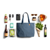 A blue tote bag surrounded by a drink bottle, sunglasses, a phone, keys, oranges, and various food items.