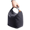 A hand holds a grey patterned cooler bag with a strap. The bag is compact and features a logo.