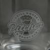 A clear glass beer glass featuring an etched logo design in a circular shape.