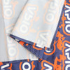 A small table runner featuring a vibrant pattern in orange and navy, with a prominent logo and neat stitching.
