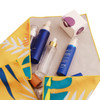 A vibrant yellow and green cloth holds various blue and clear spray bottles alongside a small white box.