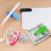 A variety of silicone magnetic clips in blue, pink, black, and green, holding a phone, papers, headphones, and money.