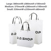 A small black and white boutique paper bag with handles, measuring 330mm x 250mm x 80mm. It features a logo.