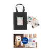 A small black vertical paper bag with knitted handles and a decorative tag, accompanied by various stickers.