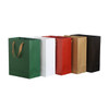 A set of small vertical paper bags in green, white, red, brown, and black, featuring rope handles.