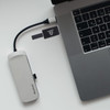 A silver flash drive connected to a laptop, featuring a logo, alongside a grey hub.