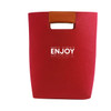 A red felt tote bag with a brown leather handle and a logo on the front.