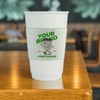A stack of white PLA double wall compostable paper cups with a colourful sleeve and branding on a wooden table.