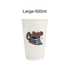 A large, 500ml white compostable paper cup featuring a colourful graphic design with books and text. The cup has a logo.