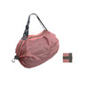 A foldable shopping shoulder bag in a soft pink shade, with a grey strap and an included compact storage pouch.