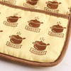 A large quilted pot holder in yellow with brown pot and "Bakery" designs, featuring a brown trim and a logo.