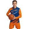 A man holding a basketball wears a long-sleeved polo shirt in blue and orange with a logo.