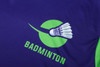 A purple and green badminton shirt featuring a shuttlecock graphic and a logo. 