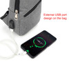 A grey travel sling chest bag with a USB port, paired with a charging phone displaying the battery percentage.