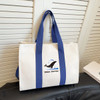 A canvas grocery shopping bag in cream with blue handles and a logo on the front.