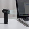 A black handheld fan with a sleek design, positioned next to a laptop on a desk. It features a logo.