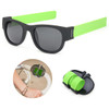 Black sunglasses with green arms, accompanied by a green silicone strap for securing them.