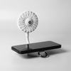 A white rechargeable fan with a flexible neck attached to a black phone stand. It features a logo on the fan.