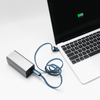 A silver charging device connected to a laptop with a blue 3-in-1 charging cable.
