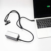 A silver charging power bank connected to a laptop with a black lanyard and cable.