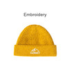 A round, yellow beanie with a ribbed design and a logo featuring mountains and text on the cuff.
