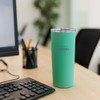 A drink bottle in mint green, with a stainless steel body and lid, sits next to a keyboard on a desk.