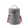 A cylindrical lunch bag in grey fabric with a brown shoulder strap and zip closure, featuring a logo.
