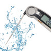 A digital instant read meat thermometer with a silver body and stainless steel probe, surrounded by splashes of water.
