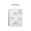 A spiral-bound folder featuring colourful unicorn illustrations on a light background, with stars and clouds. It has a logo.
