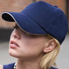 A navy blue heavy cotton sandwich cap with white trim, worn by a woman with short blonde hair.