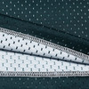 A close-up of a green and white fabric featuring a perforated texture, revealing layered materials with a stitching detail.
