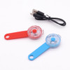 Two LED pet collar lights in red and blue, alongside a USB charging cable. Each light has a round design.