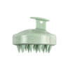 A green hair scalp massager with a textured surface and pointed bristles, featuring a hanging loop for easy storage.
