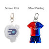 A reflective keychain in the shape of a football shirt, featuring blue and red colours with a clip attachment.