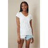 A model wearing a white women's V-neck t-shirt paired with distressed denim shorts. The shirt has a logo.